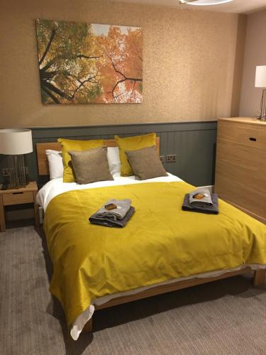 een slaapkamer met een groot geel bed met handdoeken erop bij The Tower Arms Hotel in Iver