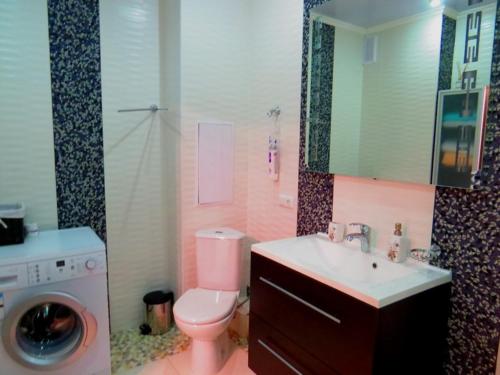 a bathroom with a toilet and a sink and a washing machine at Apartment on Svobodu ave in Sumy