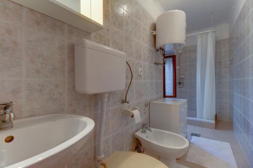 a bathroom with a toilet and a tub and a sink at Apartman Corino in Veli Lošinj