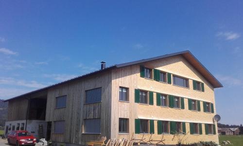 a large wooden building with a red car in front of it at Bauernhof Feurstein in Andelsbuch
