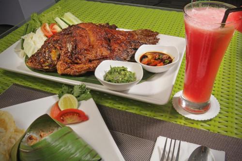 a plate of meat and a drink on a table at Whiz Prime Hotel Sudirman Cilacap in Cilacap