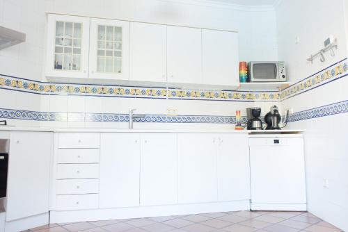 a white kitchen with white cabinets and a sink at Cal Tio Lluc in Sóller