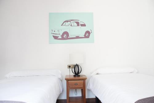 a bedroom with two beds and a small table with a car picture at Cal Tio Lluc in Sóller