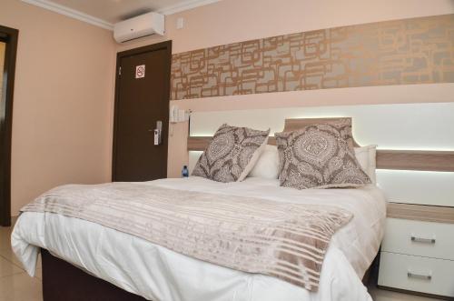 a bedroom with a large white bed with pillows at Solrand Hotel in Durban