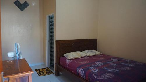 a bedroom with a bed and a table with a fan at Arriani Homestay in Karimunjawa