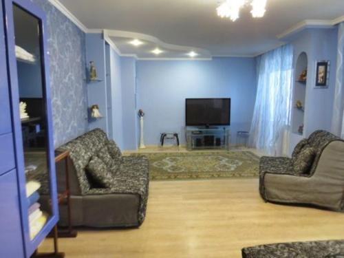 a living room with two chairs and a flat screen tv at Apartments on Kharkovskaya Street in Sumy