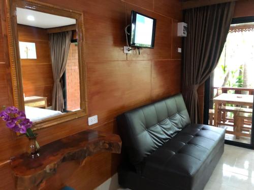 a living room with a leather couch and a mirror at Ruan Mai San Ngam Resort - SHA Plus in Nai Yang Beach