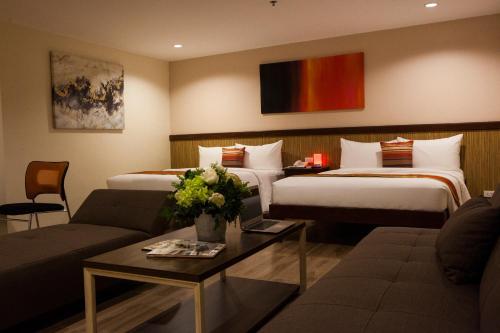a hotel room with two beds and a couch at NS Royal Hotel in Cebu City