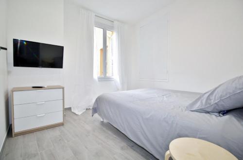 a white bedroom with a bed and a tv at Republique Garibaldi in Nice