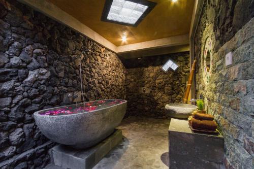 a stone bathroom with a large tub and a toilet at Jero Sebali Villa in Ubud