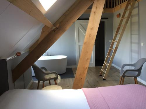 a attic bedroom with a bed and a bath tub at B&B Erve ten Dam in Ambt Delden