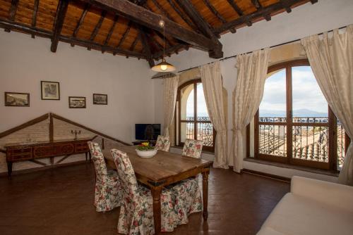 a dining room with a table and chairs and windows at Residenze al Castello Apartments in Cagliari