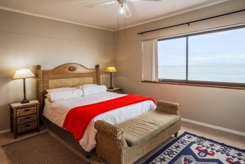 a bedroom with a bed and a chair and a window at Luxurious Beach Front in Strand