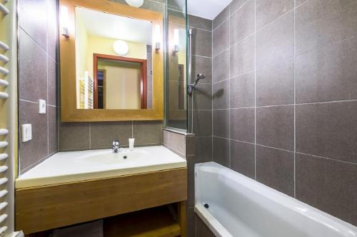 une salle de bain avec un lavabo, une baignoire et un miroir dans l'établissement Residence Aster - maeva Home, à Avoriaz