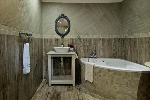 a bathroom with a tub and a sink and a mirror at De Loft Guesthouse in Piet Retief