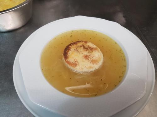 a white plate with a bowl of soup with a biscuit at Gasthof Liederhalle in Aalen