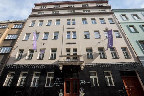 فندق ميو وينسيسلاس في براغ: مبنى أبيض طويل مع علامات أرجوانية عليه
