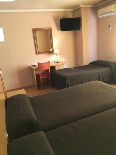 a hotel room with two beds and a table and a chair at Hotel Avenida Leganés in Leganés