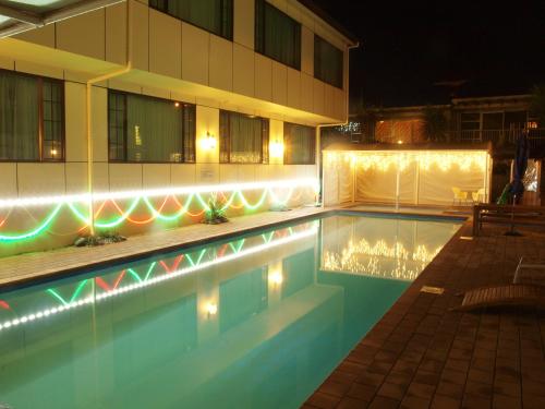 a swimming pool in front of a building at night at Albany Rosedale Motel in Auckland