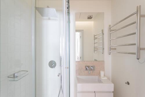 La salle de bains blanche est pourvue d'un lavabo et d'une douche. dans l'établissement FLH Baixa Cozy Apartments, à Lisbonne