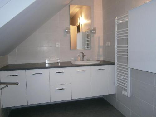 a bathroom with white cabinets and a sink at Le Jardin Fleuri in Ploemel