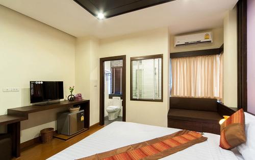 a bedroom with a bed and a television and a bathroom at Tara Place Hotel Bangkok in Bangkok