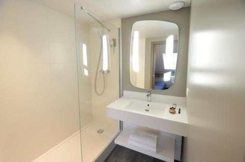 a bathroom with a sink and a shower with a mirror at ibis Maisons Laffitte in Maisons-Laffitte