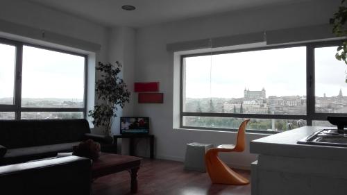 a living room with three large windows and a couch at TOLETUM low cost LOFTS diáfanos o 2dormitorios PARKING Municipal Gratis al aire libre a 100m in Toledo