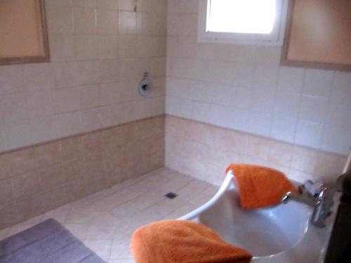bagno con vasca, lavandino e asciugamano arancione di tuscanrooms apartment a Lucca