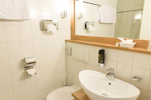 a bathroom with a sink and a toilet and a mirror at Stadthotel Berggeist in Penzberg