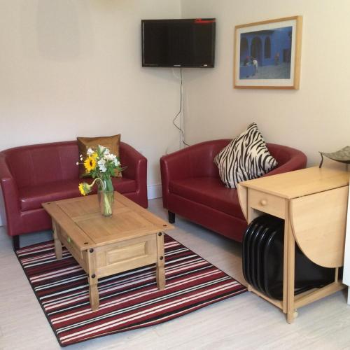 a living room with a red couch and a table at Olde Lantern Holiday Lets in Ilfracombe