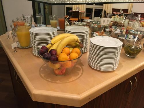 a bowl of fruit sitting on a table with plates at Stadthotel Berggeist in Penzberg