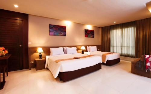 a hotel room with two beds and a television at Pattaya Loft in Pattaya Central