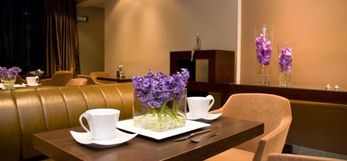 a table with a vase of purple flowers on it at Flisvos Hotel Nafpaktos in Nafpaktos