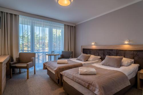 a hotel room with two beds and a balcony at Hotel *** NAT Jarosławiec in Jarosławiec