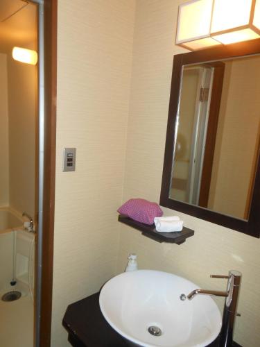 a bathroom with a white sink and a mirror at Onyado Tsutaya in Kiso