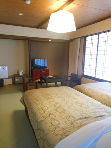 a bedroom with two beds and a table in it at Onyado Tsutaya in Kiso