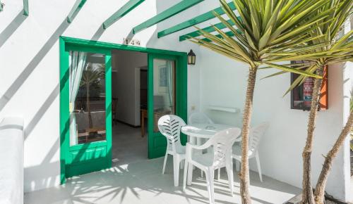 a patio with a table and chairs and a palm tree at BLUESEA Hotel Los Fiscos in Puerto del Carmen