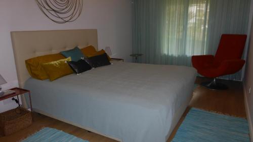 フンシャルにあるBeach Flat - Apartamento Praia Doca do Cavacasのベッドルーム1室(大型ベッド1台、赤い椅子付)