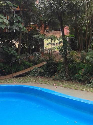 a swimming pool in front of a yard with trees at Cabañas Sueño Azul in Oberá