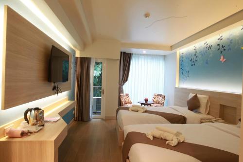 a hotel room with two beds and a television at Levana Pattaya Hotel - SHA Extra Plus in Pattaya