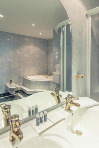 a bathroom with a tub and a sink and a mirror at Hotel Schloss Neustadt-Glewe in Neustadt-Glewe