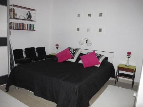 a bedroom with a black bed with pink pillows at Apartment Annika in Tivat