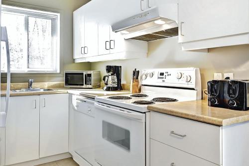 a kitchen with white cabinets and a white stove top oven at Condo 306 33 Chemin du Hameau by Les Chalets Alpins in Stoneham