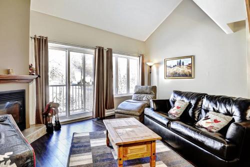 a living room with a leather couch and a table at Condo 306 33 Chemin du Hameau by Les Chalets Alpins in Stoneham