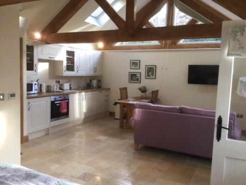 a living room with a couch and a kitchen at The Potting Shed in Warwick