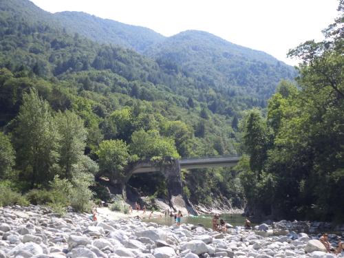 a bridge over a river with people on the rocks at B&B Casa Codega in Intragna