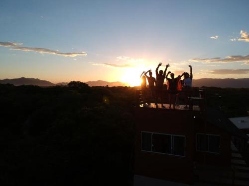 a group of people standing on top of a building at sunset at Pousada Origin in Guarda do Embaú