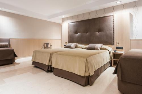 a bedroom with a large bed with a large headboard at Gran Hotel Barcino in Barcelona