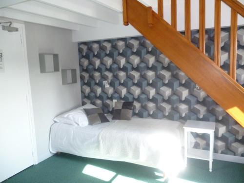 a bedroom with a bed under a staircase at Hôtel Picardia in Saint-Valery-sur-Somme